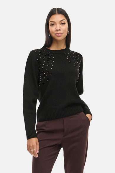 Pull noir avec col rond de Vila, orné de strass sur les épaules, associé à un pantalon marron foncé et des escarpins.