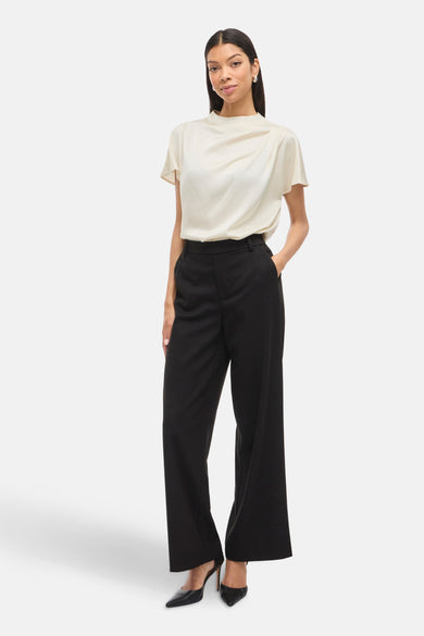Ecru blouse met korte mouwen van VILA®, gecombineerd met zwarte, wijde pijpen en pumps.
