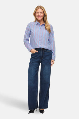 Blauw overhemd met lange mouwen van VILA®, gestreept, gedragen met donkere jeans en zwarte hakken.
