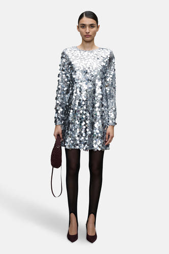 Robe d'argent avec des manches longues de VILA®, ornée de paillettes et associée à des sous-vêtements noirs et des escarpins bordeaux.