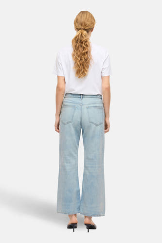 PALMA lichtblauwe denim wijde jeans van VILA, gezien van achteren, met een wit T-shirt en zwarte hakken.