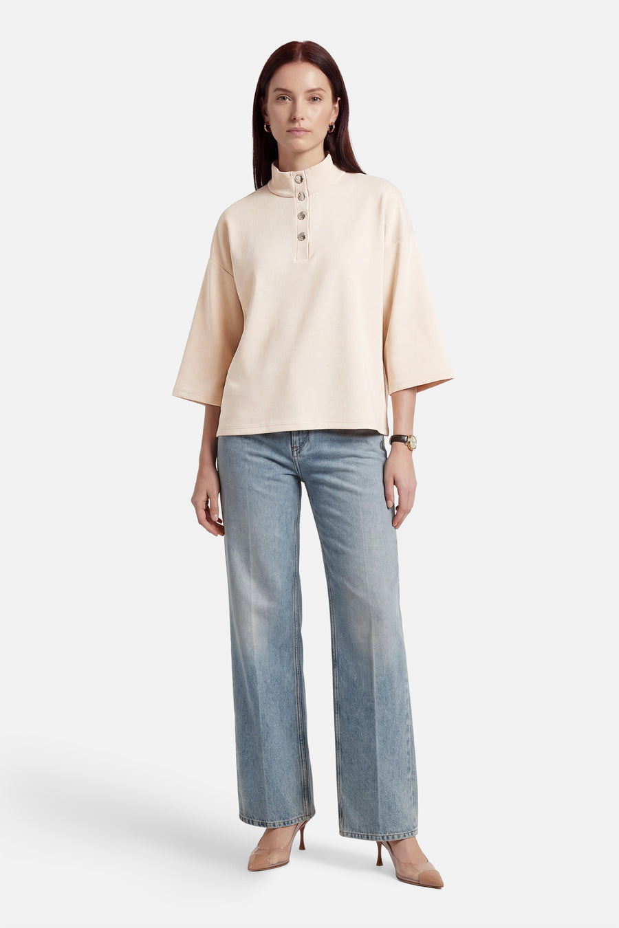 Beige sweater van VILA®, met een knoopsluiting en wijde mouwen, gecombineerd met een blauwe jeans en hoge hakken.

