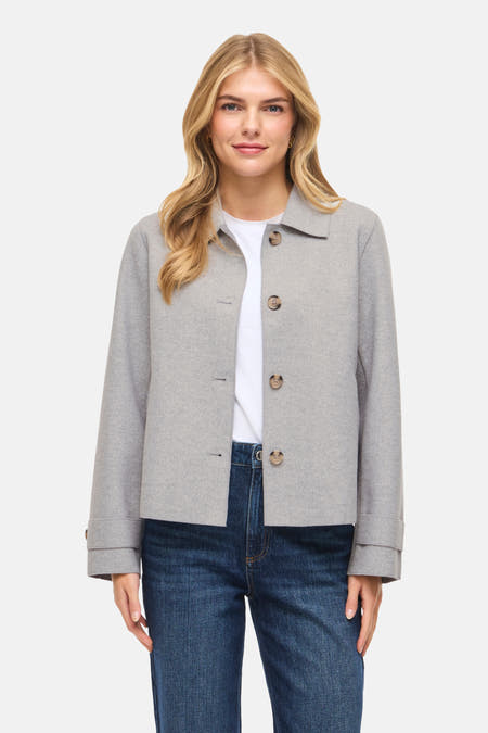 Grijze jas van VILA®, met knoopsluiting, gedragen over een wit shirt en een blauwe jeans.
