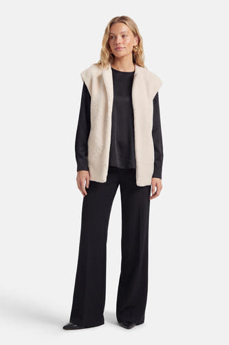 Manteau beige de VILA®, porté sur un haut noir et un pantalon, avec des boucles d'oreilles dorées.