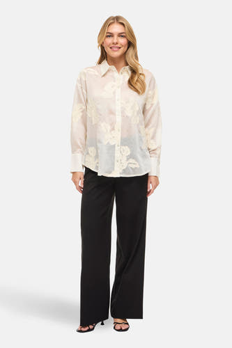 Beige overhemd (lange mouwen) van Vila, met bloemendetails en gecombineerd met een zwarte pantalon en hakken.
