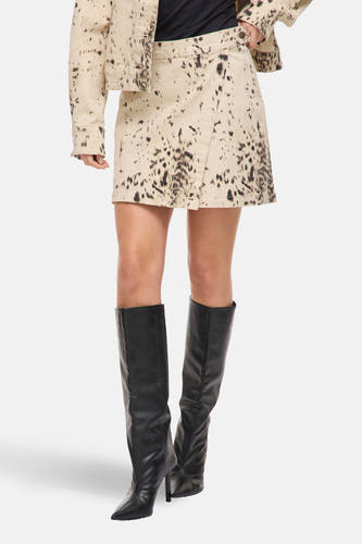 Beige korte rok van Vila, met donkere vlekken en een overslagdetail, gecombineerd met zwarte, hoge laarzen.