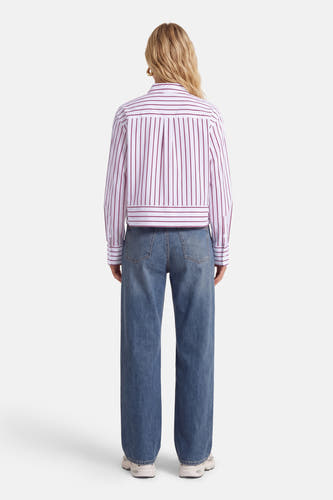 Chemise à rayures rouges et blanches (manches longues) de Vila®, vue de dos, combinée avec un jean bleu et des baskets blanches.