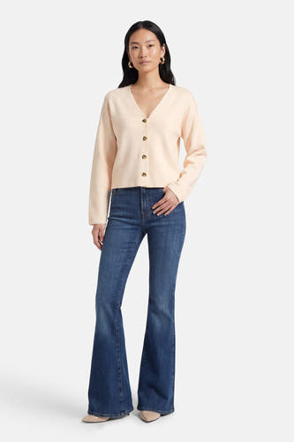 Ecru gilet van VILA®, met lange mouwen en gouden knopen, gecombineerd met blauwe jeans met uitlopende pijpen.