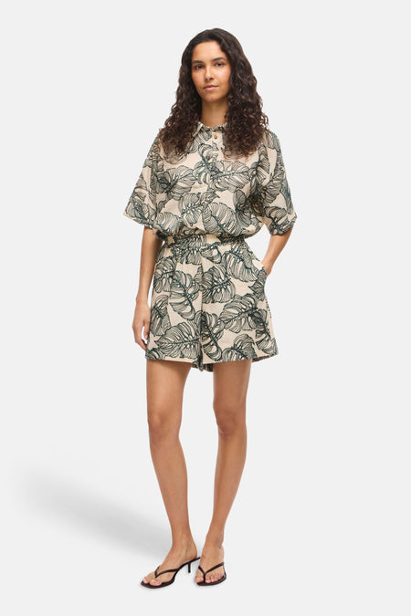 Lichtbruine short met groen bladmotief van VILA, met korte mouwen, kraag en elastische taille, gedragen met zwarte sandaaltjes.