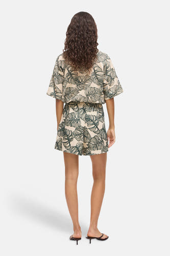 Beige short met groen bladpatroon van VILA, van achteren gezien met bijpassend shirt en sandalen.