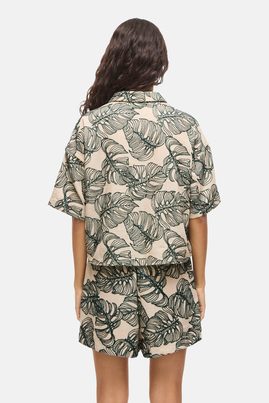 Lichtbeige overhemd met korte mouwen met groen bladpatroon van VILA®, van achteren gezien, gedragen met bijpassende shorts.