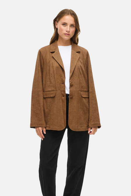 Bruine jas van VILA®, met revers en lange mouwen, gecombineerd met een wit shirt en zwarte broek.
