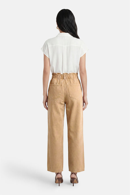 Bruine broek van VILA met paperbag taille, wijde pijpen en opgestikte achterzakken, van achteren gezien, gedragen met een wit overhemd en bruine hakken.