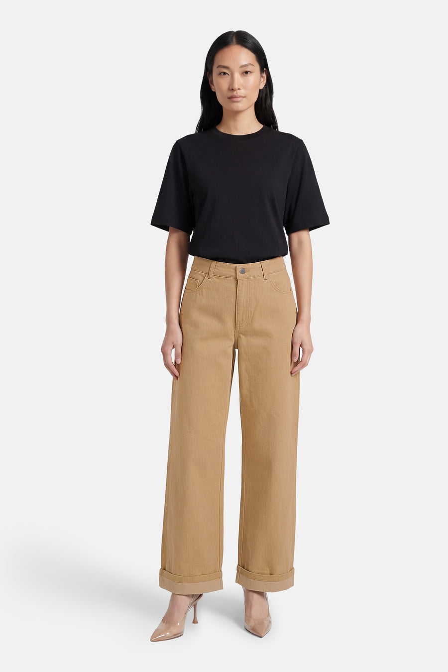 Beige gekleurde jeans van VILA®, met wijde pijpen en opgerolde zoom, gecombineerd met een zwart T-shirt en transparante pumps.
