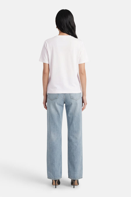 Wit T-shirt met korte mouwen van VILA®, gezien van achteren, gecombineerd met blauwe jeans en zwarte hakken.