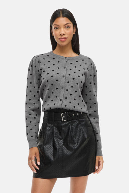 Veste grise de VILA®, avec des taches noires, portée avec une mini-jupe noire à cece et des sandales noires.