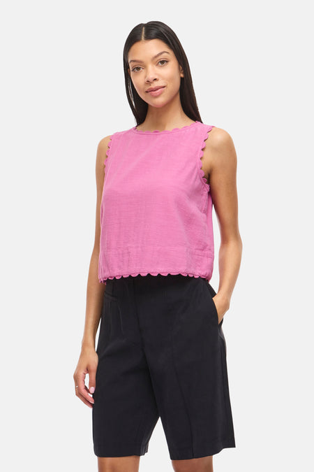 Chemisier sans manches rose de VILA® avec bords festonnés, porté avec un short noir et des sandales ouvertes noires.