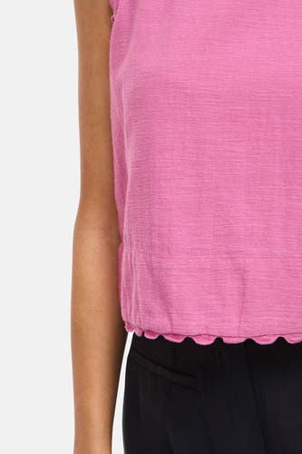 Roze mouwloze blouse van VILA® met een geweven textuur, geschulpte zoom en gerimpelde taille, gedragen met een zwarte broek.