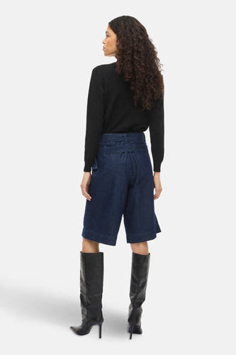 Shorts de denim bleu marine de VILA, associés à des bottes noires longues et une veste noire, vu de dos.