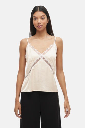 Ecru mouwloze blouse van VILA, met kanten details aan de halslijn en schouderbandjes, gedragen met een zwarte broek.
