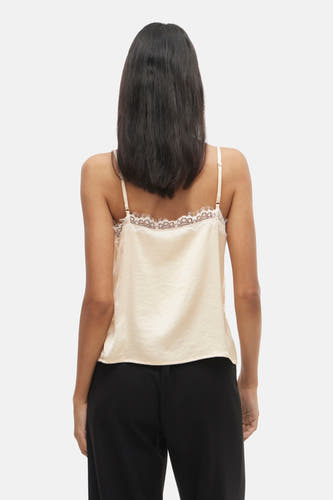 Ecru blouse zonder mouwen van VILA, met kanten details, gecombineerd met een zwarte broek.