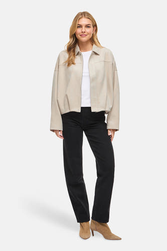 Beige korte jas van VILA®, met lange mouwen en gedragen over een wit shirt en een zwarte jeans.
