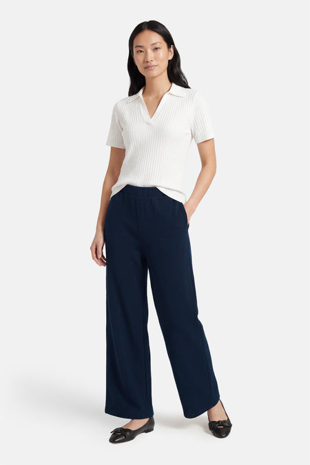 Blauwe broek van VILA®, met wijde pijpen en gecombineerd met een witte top en zwarte ballerina's.
