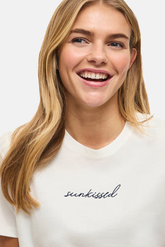 Witte korte mouw t-shirt van VILA® met zwarte geborduurde tekst 'suntkissed', gedragen door model, close-up voorzijde