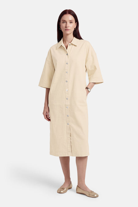Robe beige à manches courtes de VILA®, avec fermeture à boutons et poche latérale, combinée avec des ballerines dorées.