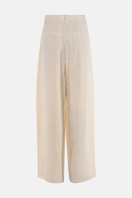Beige broek van VILA® met een subtiel bloemmotief en wijde pijpen, gezien van achteren.
