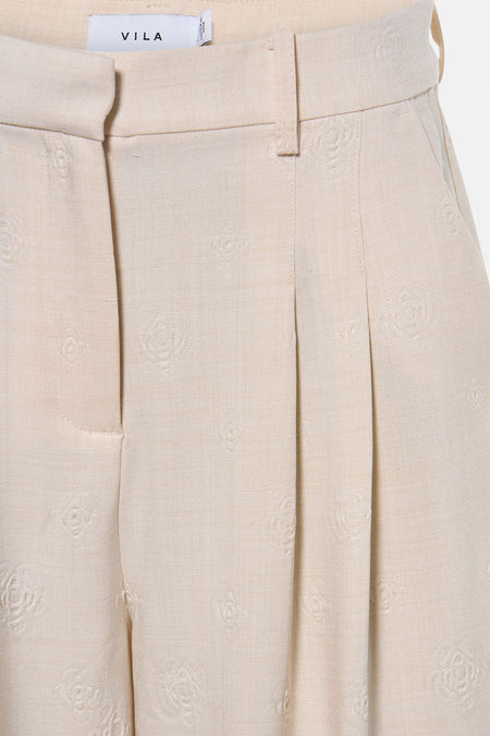 Pantalon beige de VILA avec motif floral subtil et plis sur le devant.