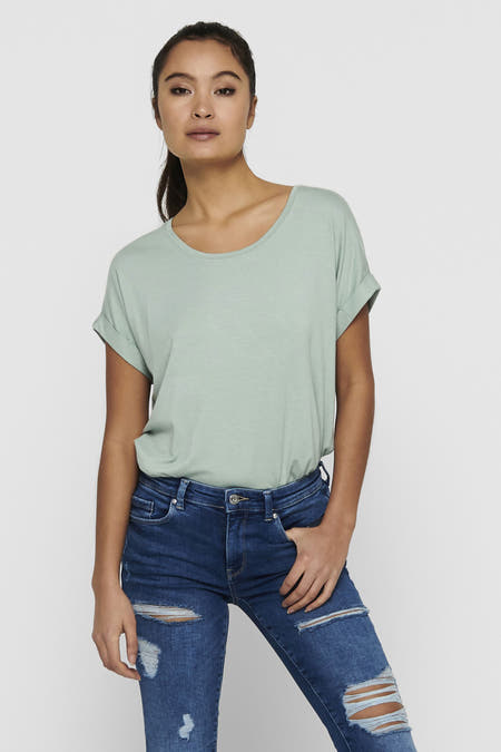 Groen T-shirt van ONLY, met korte mouwen en omgerolde manchetten, gedragen met blauwe ripped jeans.
