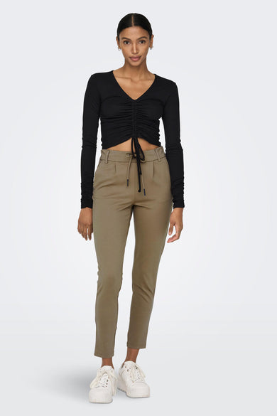 Bruine chino broek van ONLY® met trekkoord taille, strakke pasvorm en korte pijpen, gedragen met zwart topje en witte sneakers.