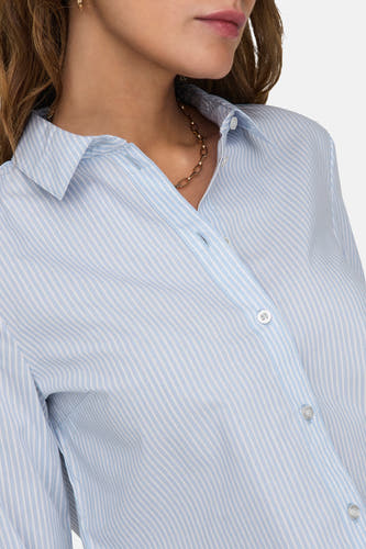 Chemise bleue rayée avec longues manches de JDY, portant une chaîne d'or et des boucles d'oreilles.