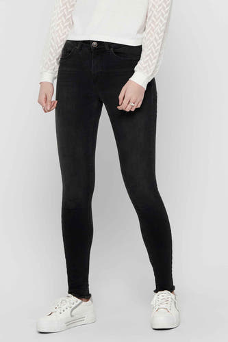 Zwarte skinny jeans van ONLY, met gerafelde zomen, gedragen met witte blouse en witte sneakers.