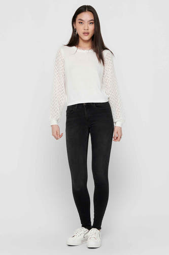 Zwarte skinny jeans van ONLY, met lange pijpen en gedragen met een witte top en sneakers.