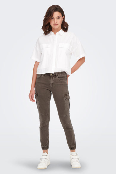 Bruine broek van ONLY, met cargozakken en gecombineerd met een wit overhemd en witte sneakers.

