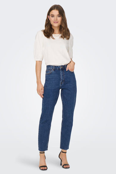 Donkerblauwe mom jeans van ONLY, met hoge taille en onafgewerkte randen, gecombineerd met een witte top en zwarte sandalen.