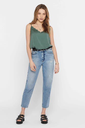 Groene mouwloze blouse van ONLY, gedragen met jeans, een zwarte riem en sandalen met plateauzool.