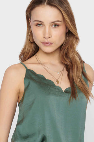 Mouwloze groene blouse van ONLY, met een geschulpte halslijn en gouden sieraden.
