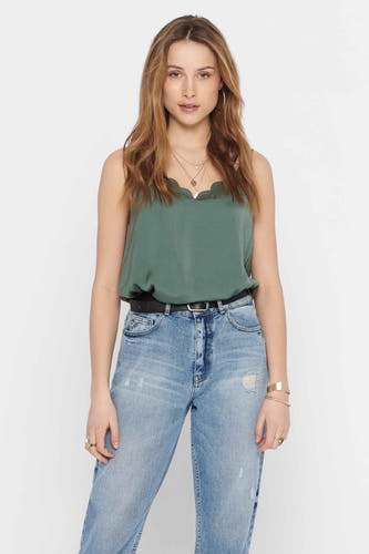Groene mouwloze blouse van ONLY, gedragen met een zwarte riem en jeans met een lichte wassing.
