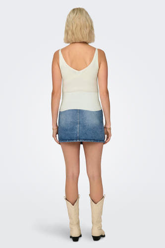 Witte tanktop van JDY, met een geribbelde textuur en een V-hals aan de achterkant, gedragen met een denim rok en cowboylaarzen.
