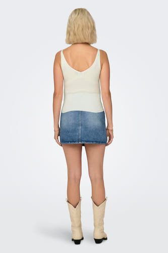Witte tanktop van JDY, gecombineerd met een denim minirok en beige cowboylaarzen, achteraanzicht.