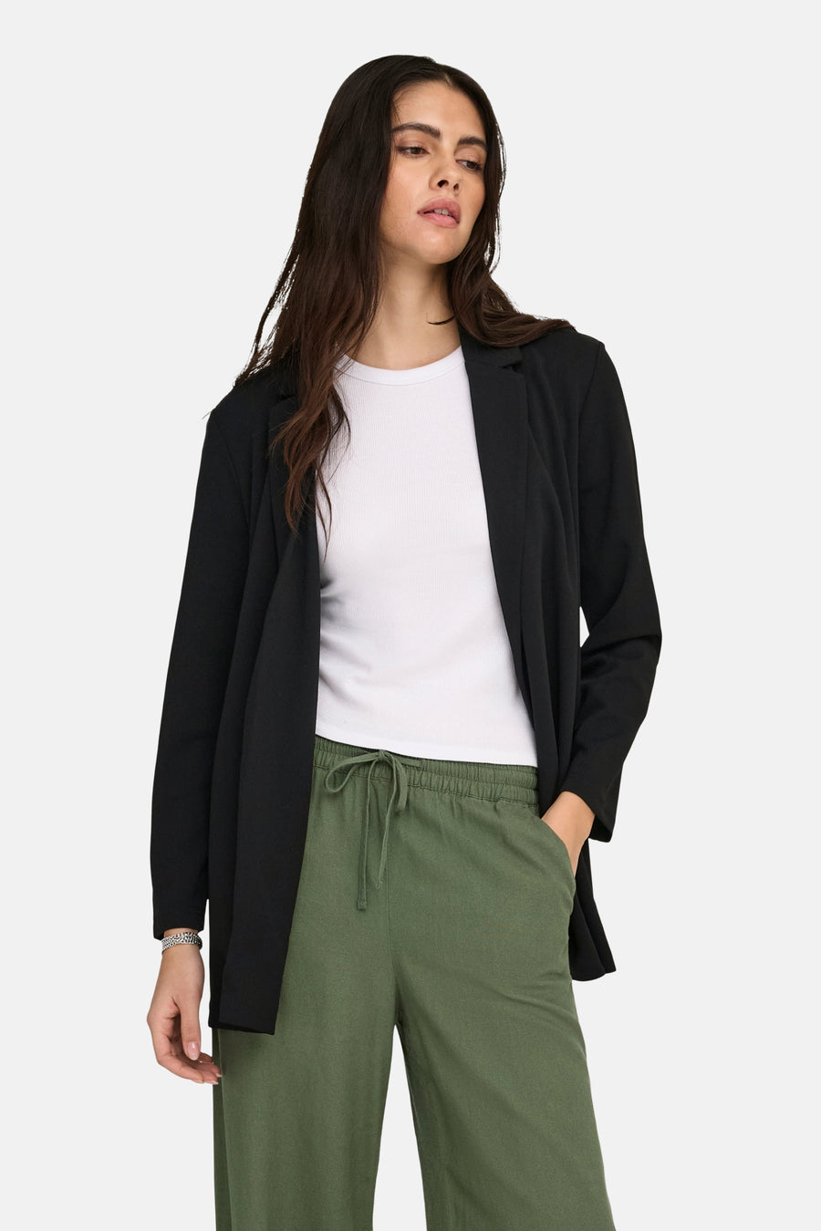 Femme en blazer noir, chemise blanche et pantalon vert.