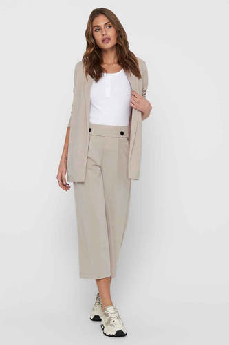 Grijze blazer van JDY, gedragen met een witte top en beige culottebroek.
