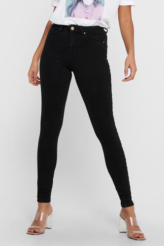 Jean skinny noir ONLY®, porté avec un T-shirt blanc imprimé et des talons transparents.