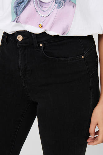 Jeans skinny noirs d'ONLY, avec des boutons dorés et un t-shirt blanc avec un imprimé.