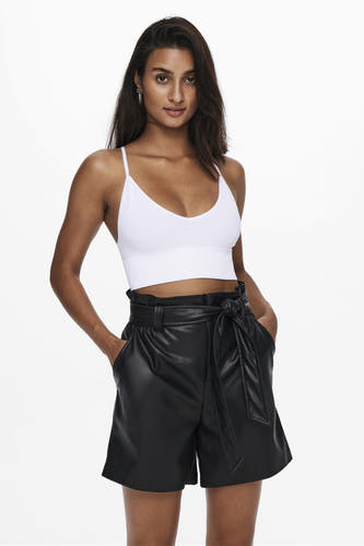 Buste blanche ONLY, avec de fines bretelles, portée avec un short noir à taille haute et ceinture à nœud.