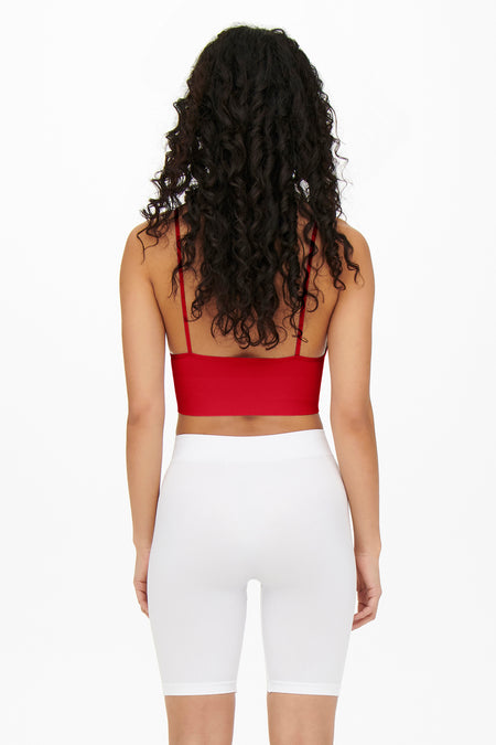 Maillot de corps rouge ONLY, avec des fines bretelles et porté avec un short de sport blanc.