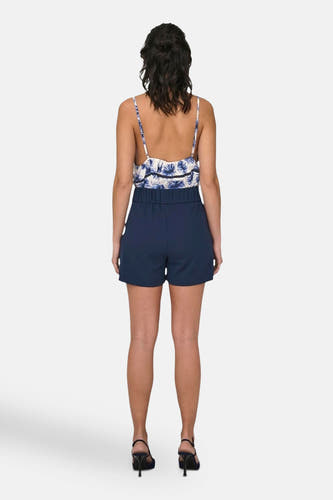 Blauwe short van JDY, met hoge taille en gedragen met een bloemrijk topje en zwarte hakken.
